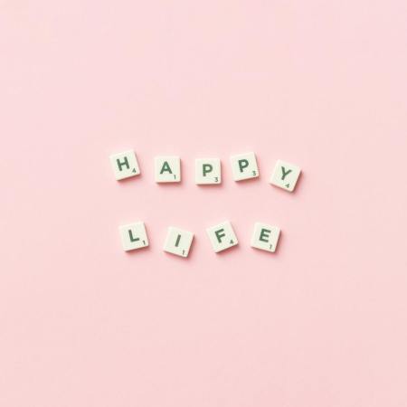 scrabble letters on a pink background spelling happy life