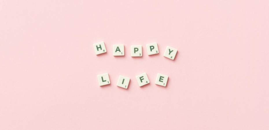 scrabble letters on a pink background spelling happy life
