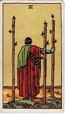 A tarot card depicting a figure in a red cloak and green cape, standing with their back to the viewer, holding onto one of three upright wooden staffs in a barren landscape.